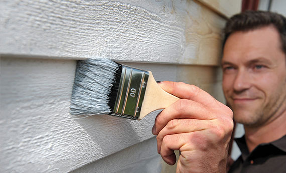 [Translate to EN:] Osmo Farbe und Anstriche - angeraute Holzfassade am Haus wird mit Osmo Farbe weiß gestrichen OSMO